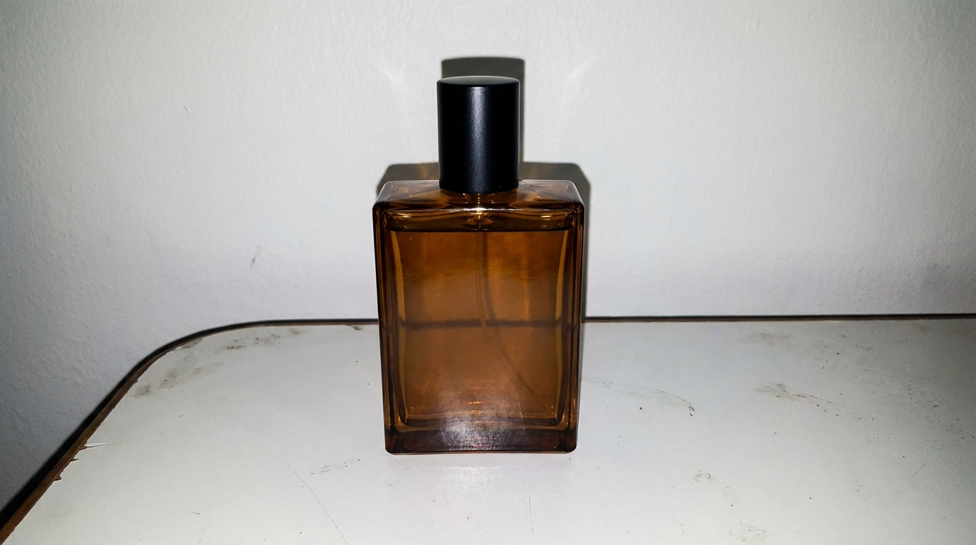 Ordinary supplier photo of an amber perfume bottle on a plain table